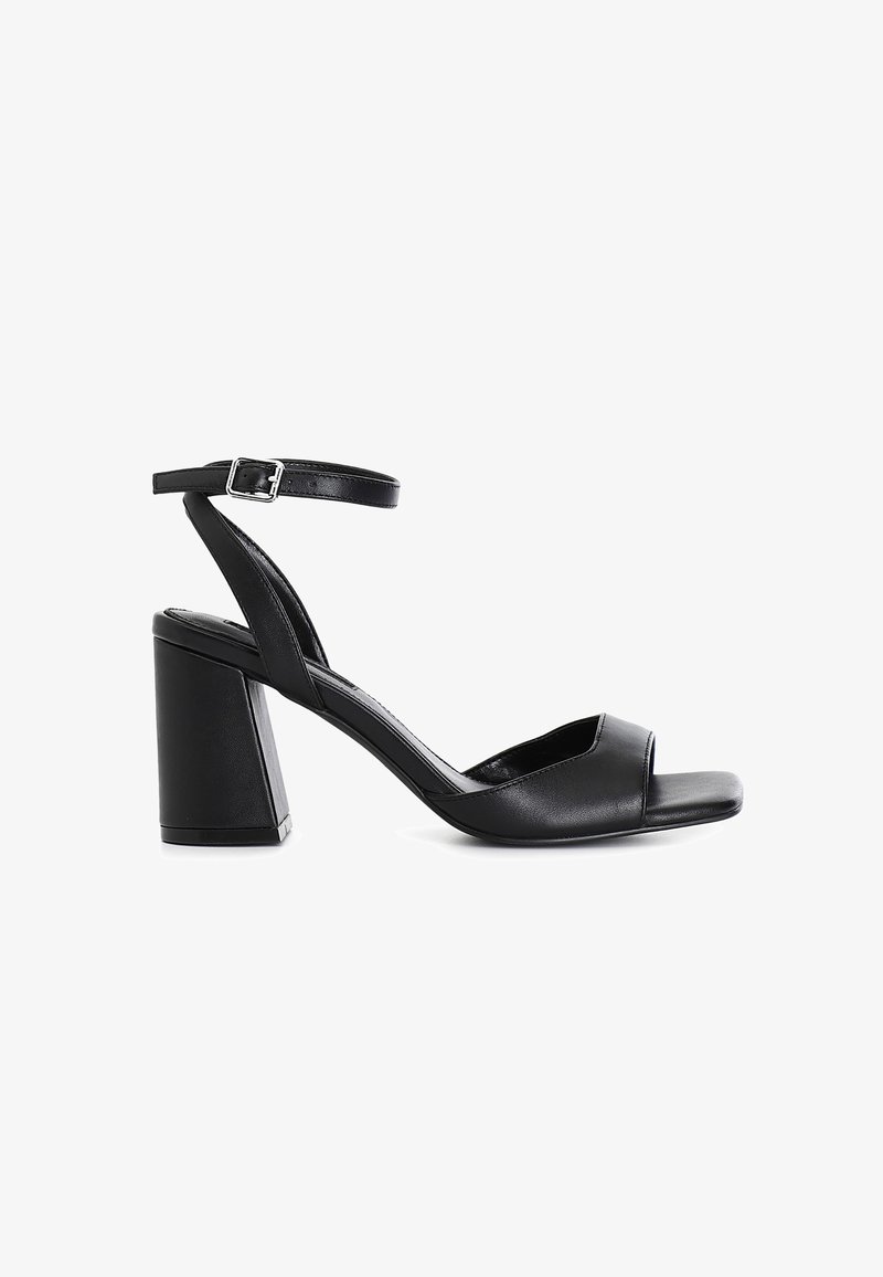 Sandales à talons en cuir noir avec un bout carré et une large sangle de cheville fermée par une boucle métallique ; un talon bloc épais complète le design.