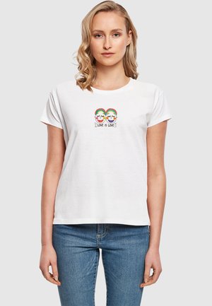 T-shirt en coton blanc avec un design brodé coloré représentant deux visages souriants, avec le texte "L'AMOUR EST L'AMOUR" en dessous. Manches courtes, coupe décontractée.