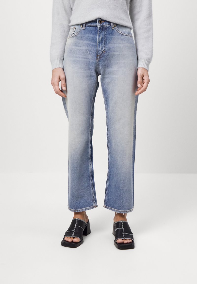 Světle modré džíny s vysokým pasem, rovného střihu, s vybledlým vzhledem a surovým lemem. V kombinaci s černými sandály na podpatku.