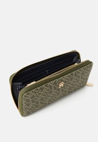 Green patterned wallet with a zip closure. Features a textured exterior, gold-tone hardware, and a spacious interior with card slots.