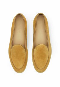 Zamszowe mokasyny w musztardowym kolorze z okrągłym noskiem i gładkimi skórzanymi akcentami wokół otworu. Płaskie podeszwy, minimalistyczny design.