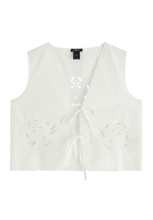 Top corto bianco con scollatura a V, bordi a scallop e ricami floreali. Presenta una chiusura con lacci sul davanti e dettagli intagliati intricati.