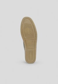 Suela de zapato de goma con un patrón texturizado que presenta surcos y elevaciones. El color es marrón claro con marcas visibles para el agarre.
