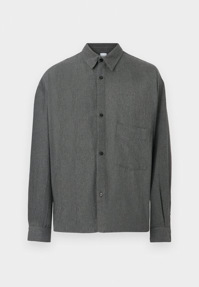 Πουκάμισο μακρυμάνικο σε σκούρο γκρι καρό με κουμπιά, γιακά και τσέπη στο στήθος, σε απλό φόντο.