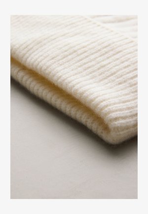 Kremfarvet strikket hue med ribbet tekstur, lavet af blødt uld. Inkluderer en dobbeltkant og en glat finish, velegnet til koldere vejr.