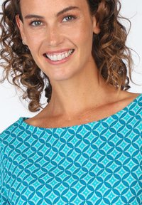 Blau gemusterte Bluse mit einem geometrischen Design aus Rauten und Sechsecken. Leichter Stoff mit einer glatten Textur und einem weiten Ausschnitt.