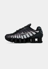 Sapatilha de corrida Nike com um cabedal em malha preta, design em degradê que vai do escuro ao claro, detalhes reforçados e uma sola distinta e robusta.