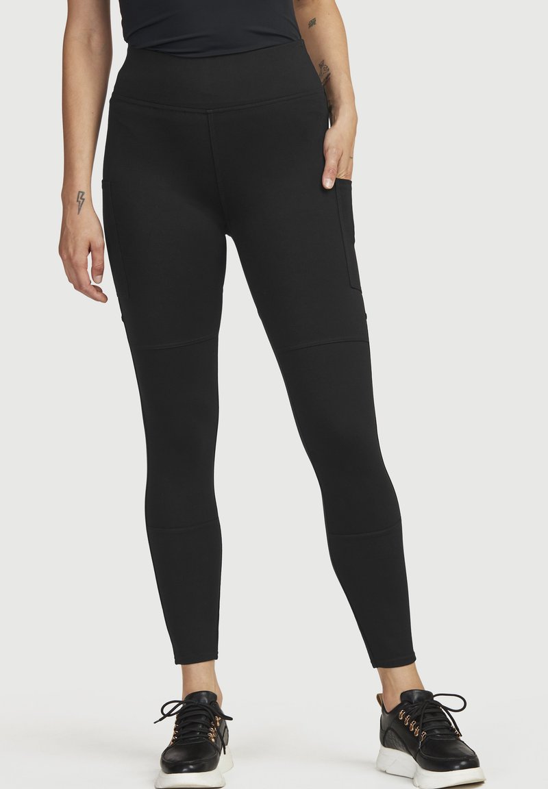Zwarte high-waisted legging gemaakt van een gladde stretchstof met zijzakken, met een aansluitend ontwerp en gestikte paneeldetails.