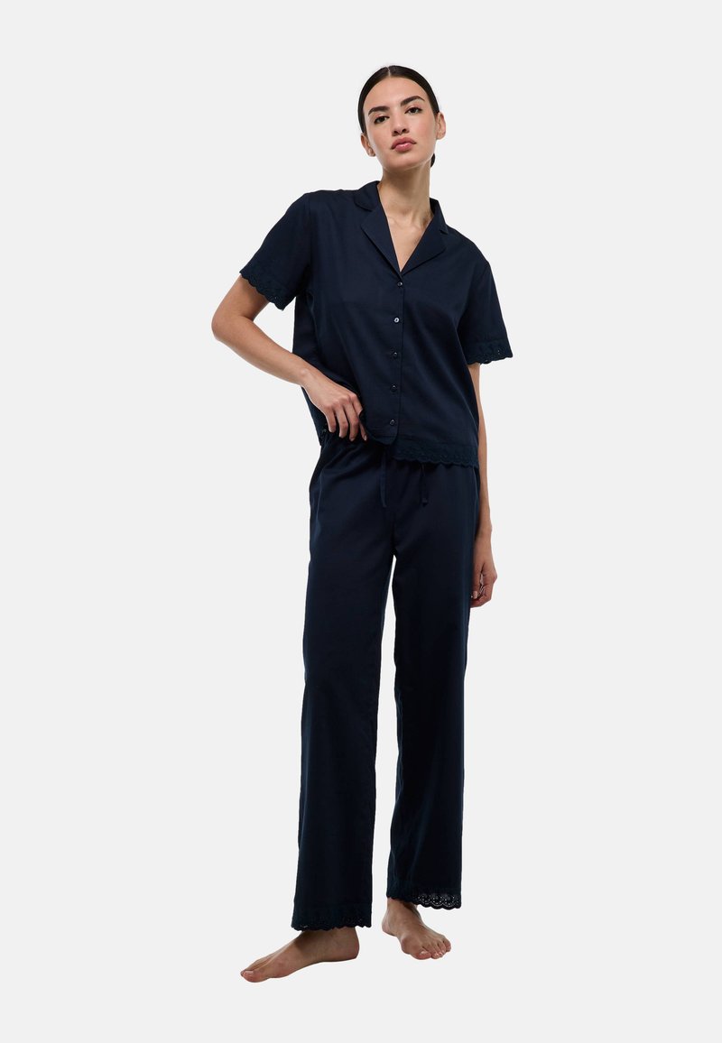 Ensemble de pyjama bleu marine en tissu doux, comprenant une chemise à boutons à manches courtes et un pantalon ample avec de la dentelle aux ourlets.