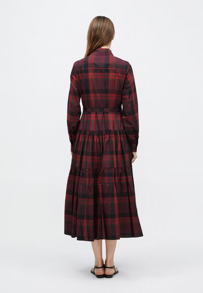 Garš pleda kleita bordo un melnā krāsā ar pieguļošu augšdaļu, garām piedurknēm un kārtainu svārku ar volāniem apakšmalā.