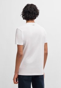 White cotton t-shirt featuring a crew neck and short sleeves, with a small "HUGO" logo on the back near the neckline.