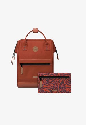 Rucksack aus rostfarbigem Stoff mit abgerundetem Oberteil, vorderer Reißverschlusstasche und einem abnehmbaren, gemusterten Beutel mit Blättern-Design.