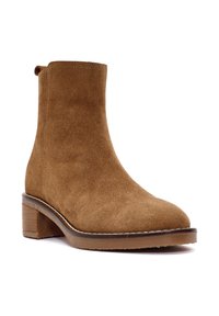 Stivaletto in suede marrone con punta rotonda, tacco impilato e cuciture semplici. Presenta una texture liscia e un design alto fino alla caviglia.