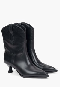 Czarne skórzane botki za kostkę z ostrym noskiem, smukłym obcasem blokowym i wzornictwem w stylu western. Gładka powierzchnia z subtelnymi detalami przeszyć.