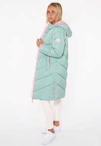 Langer, hellgrüner Puffermantel mit rosa Akzenten, Chevron-Muster, Reißverschluss vorne und zwei Seitentaschen. Mit Kapuze und markierten Kordeln.