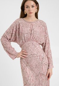 Roze paillettenjurk met een losse fit, lange mouwen en ingewikkelde kraalpatronen op zachte stof; de aansluitende taille accentueert de silhouet.