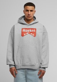 Grå hettegenser med frontlomme, som har en stor rød "Market"-logo. Laget av bomull, avslappet passform, og ribbet mansjetter og kant.