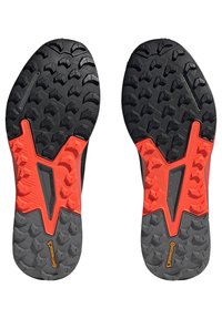 Zwarte en oranje rubberen schoenzolen met een textuur, robuust gripontwerp. Voorzien van een uitgesproken profielpatroon voor tractie en stabiliteit.