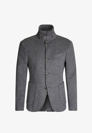 Szara kurtka z wysokim kołnierzem, zapinana na zamek błyskawiczny i pięć guzików. Posiada kieszeń na piersi oraz dwie kieszenie z przodu. Materiał o fakturze.