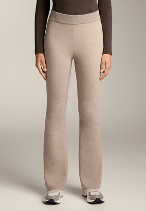 Beige Weitbein-Hosen aus weichem, strukturiertem Strickmaterial mit einem breiten, gerippten Bund, kombiniert mit hellen Sportschuhen.