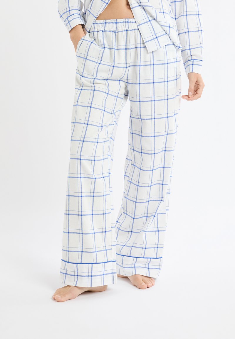 Pantalon de pyjama à carreaux blancs et bleus, doté d'une taille élastique, de poches latérales et d'une coupe décontractée avec des jambes légèrement évasées.