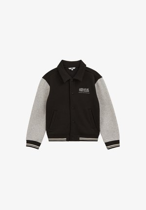 Veste varsity noire et grise avec fermeture à boutons, poignets et ceinture rayés, et texte "AHEAD OF THE GAME" sur la poitrine.
