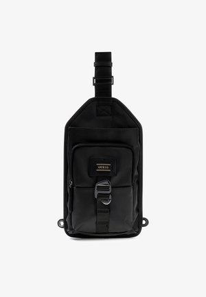 Fekete nylon válltáska téglalap alakú, elülső cipzáras zsebbel, állítható pánttal és arany logóval. Simább textúra, minimális dizájn.