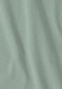 Light green cotton fabric with a smooth texture and a fine knit. The material shows soft drapes and subtle sheen. No patterns or accents visible.