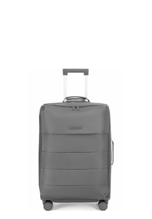 Valise souple grise debout avec poignée télescopique étendue et quatre roues pivotantes visibles sur fond blanc.
