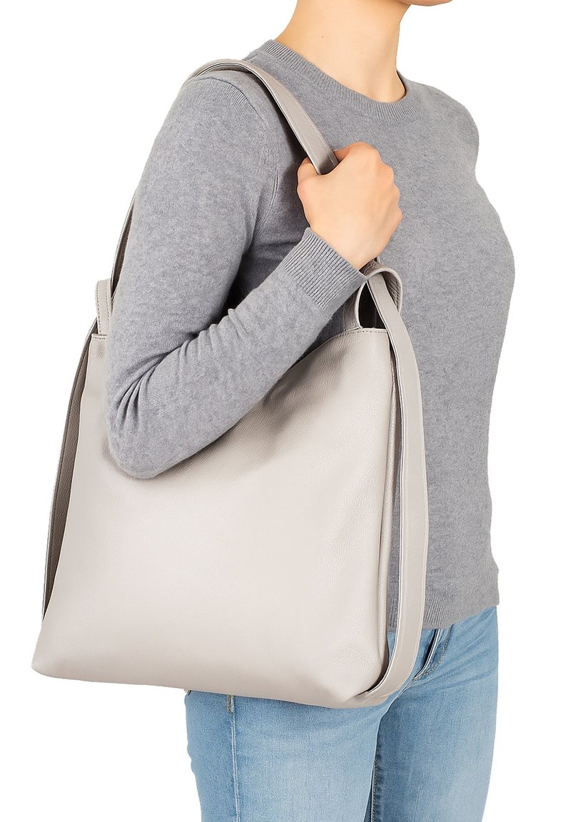Grijze leren tote bag met een zachte textuur. Voorzien van lange handvatten en een minimalistisch design. Effen grijze kleur, geen zichtbare patronen of hardware.