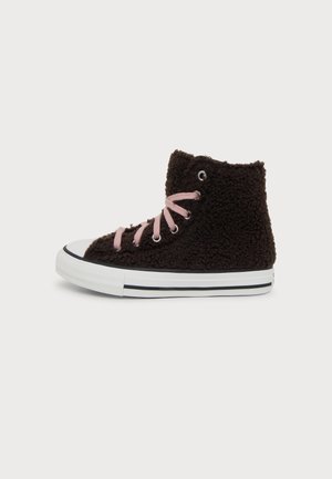 Baskets montantes noires à l’aspect duveteux, avec des lacets roses, un embout en caoutchouc blanc et une semelle blanche à rayure noire, vues de profil.