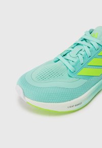 Tirkizne sportske cipele s mrežastim gornjištem, zelenim akcentima, teksturiranom površinom, zaobljenim vrhom i oznakom "LIGHT BOOST" na potplatu.