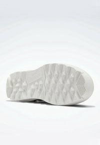 White sneaker sole with deep diamond and ridge tread patterns and Reebok logo embossed near the heel.