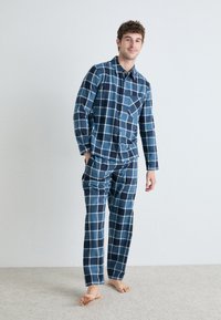 Ensemble de pyjama bleu et blanc à carreaux en tissu doux, comprenant une chemise à boutons avec une poche poitrine et un pantalon élastique assorti.