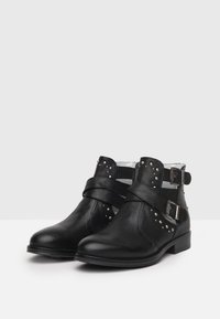 Zwarte leren enkelboots met zilveren studs, gekruiste riemen en metalen gespen. Lage hak met een gladde afwerking en een eenvoudige te ontwerp.