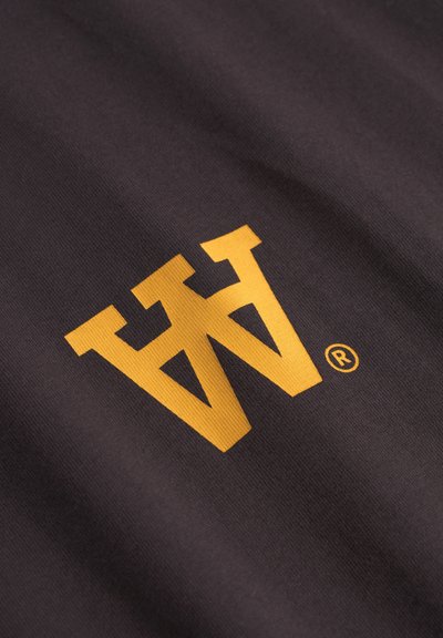 Zwarte stof met een opvallend gele logo met een gestileerde "W." Het materiaal lijkt glad met een gestructureerd weefpatroon.