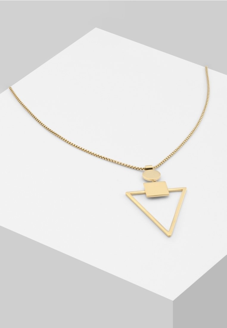 Collier en or avec pendentif géométrique comprenant un cercle, un carré et un triangle ouvert sur une surface blanche inclinée.