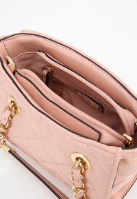 Quilted pink handbag with gold hardware, featuring a double chain strap, and two inner compartments lined with soft fabric.