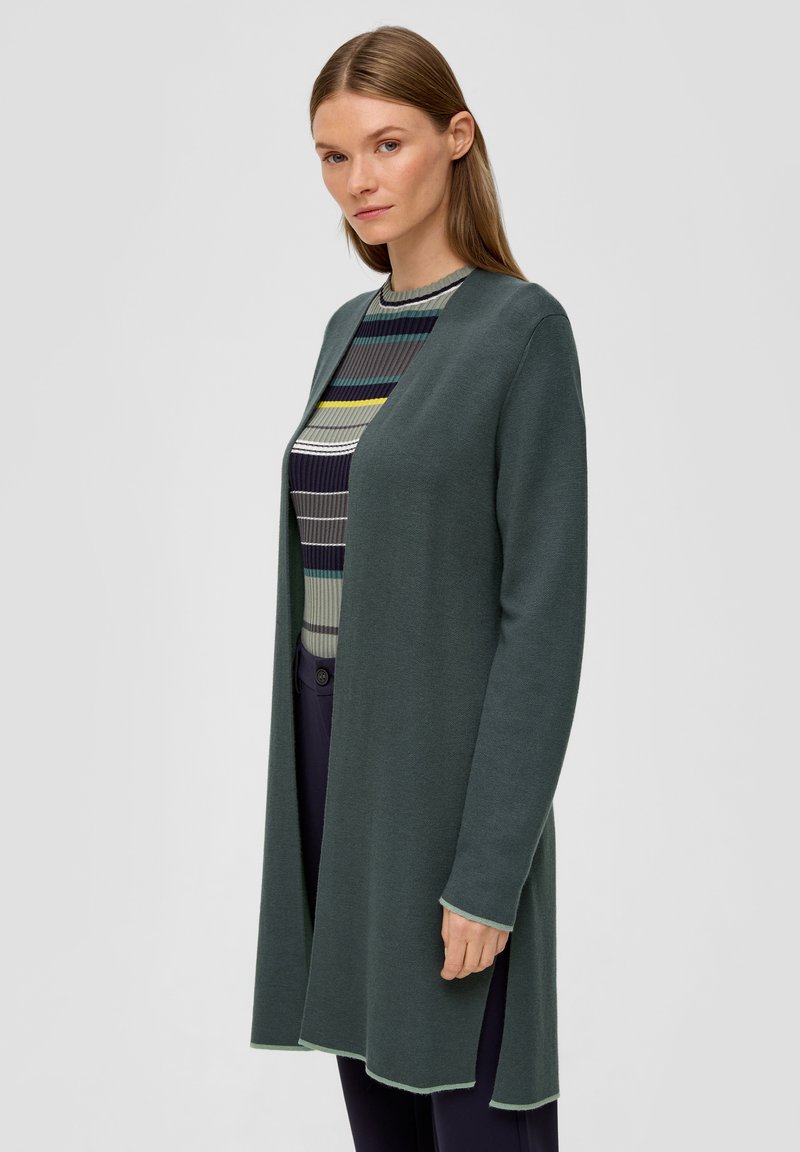 Cardigan long à l'avant ouvert en vert foncé, fabriqué en tissu tricot doux. Présente une bordure arrondie et des coutures contrastées en vert clair.