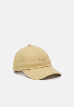 Casquette de baseball marron clair avec une visière incurvée et un petit logo brodé sur le devant côté gauche sur un fond uni.