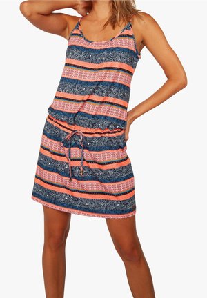 Femme portant une robe sans manches longueur genou avec des rayures horizontales dans des motifs corail, bleu, noir et blanc, posant avec les mains sur la tête et la hanche.