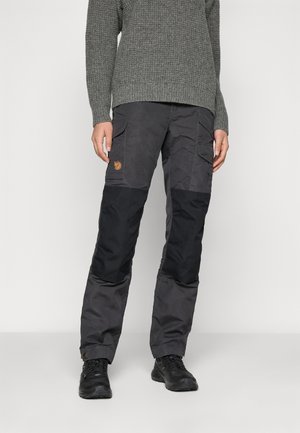 Grijze gebreide trui met lange mouwen, gecombineerd met zwart-grijze cargobroek met zijzakken en een leren logo patch.