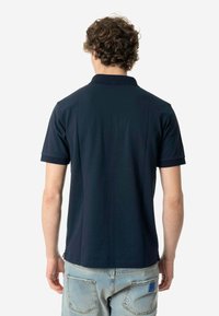 Polo a maniche corte blu navy con colletto classico e un tessuto morbido e texturizzato. Presenta un design semplice senza loghi o motivi visibili.