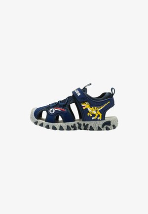 Sandalo per bambini blu navy con grafica di dinosauro, cinturini in velcro, dita aperte e suola grigia robusta progettata per il gioco all'aperto.