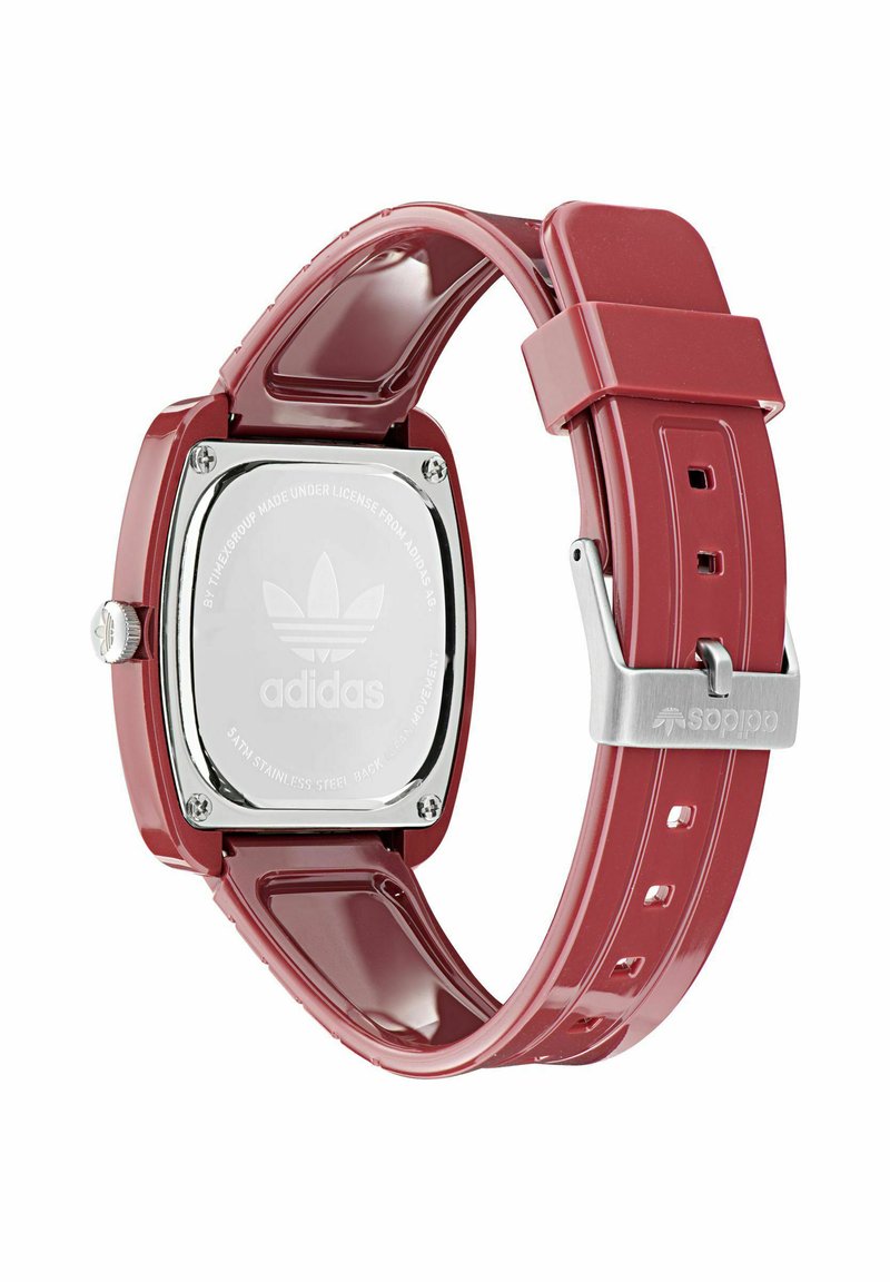Orologio quadrato rosso con retro in metallo lucido, cinturino in silicone e fibbia argento. Presenta il logo Adidas e numerosi fori di regolazione del cinturino.