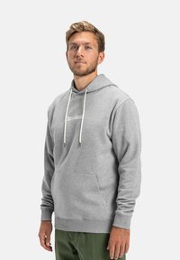 Hoodie gris avec une poche kangourou à l'avant, des cordons blancs et un logo discret sur la poitrine. Tissu doux et coupe décontractée.