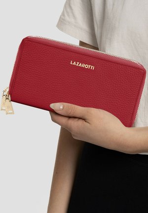 Cartera de cuero texturizado rojo con un zipper dorado y un logo. Presenta pequeños acentos de hardware dorado y una forma rectangular.