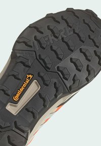 Svart gummisula med djupa greppknoppar, en central Continental-logotyp och en orange detalj, med texturerade ytdetaljer.