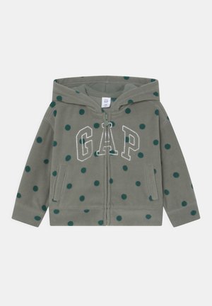 Sweat à capuche en polaire verte avec des pois vert foncé, fermeture éclair à l'avant, deux poches, et "GAP" brodé en blanc sur la poitrine.
