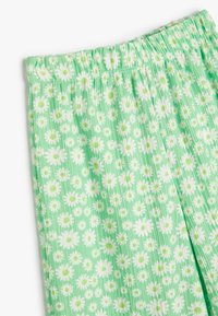 Hellgrüne Schlafanzughosen mit einem floralen Muster aus weißen Gänseblümchen, einem elastischen Bund und einem strukturierten, atmungsaktiven Stoff.